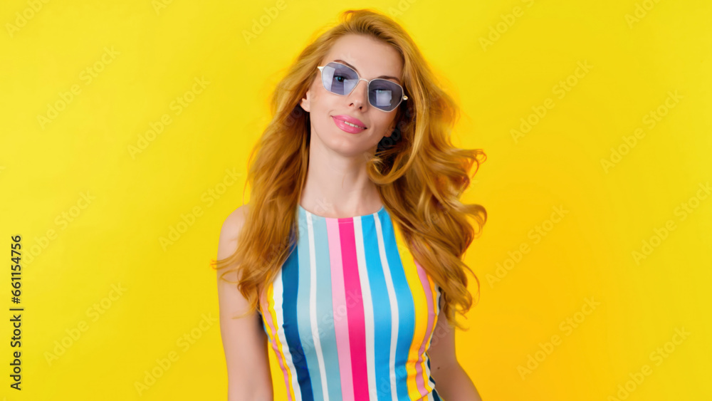 Fashionable redhead woman with smiling face for confidence, positivity, beauty, advert. Relaxed lady posing looking at camera, pride emotion, trendy makeup, vivid outfit in studio on yellow background