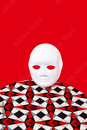White mask on table near red wall