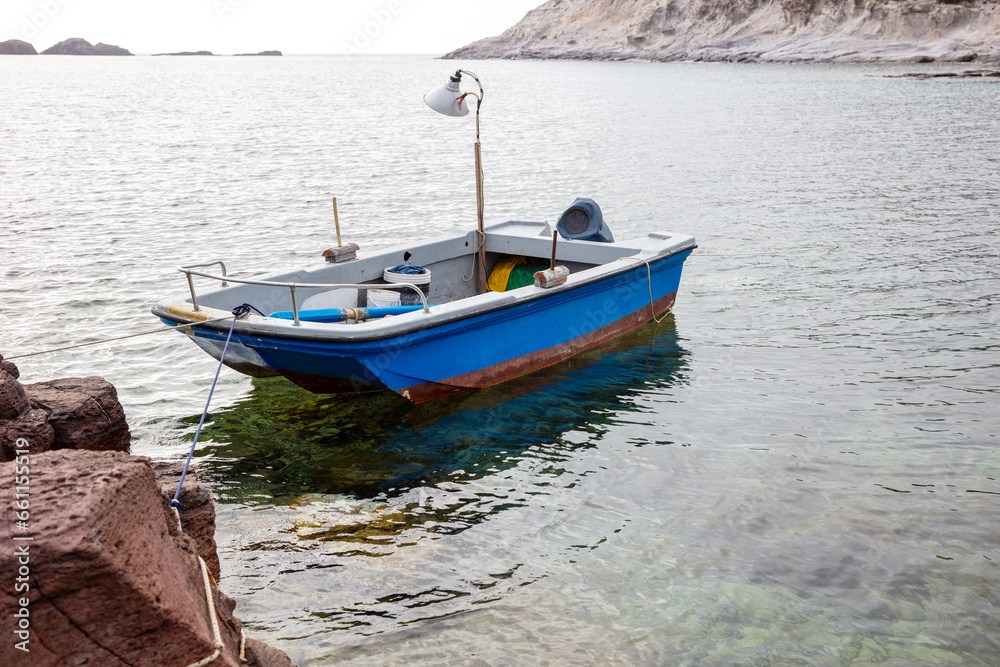 beautiful blue boat is moored to a rock