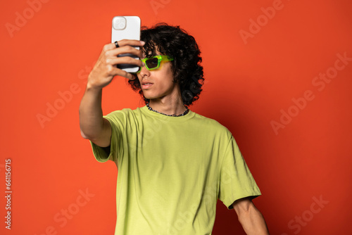 Happy young ethnic man taking selfie with smartphone photo
