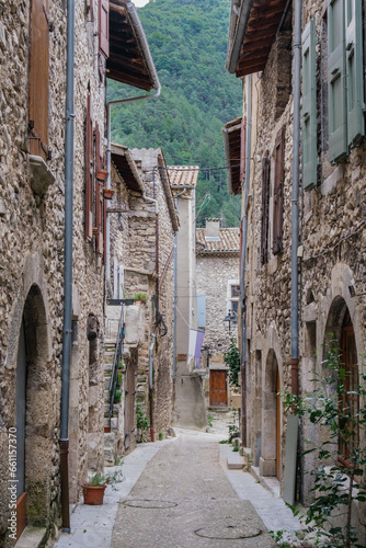 Fototapeta Naklejka Na Ścianę i Meble -  Narrow street and old house stone facades with shutters in the medieval village of Chatillon en Diois, in the south of France (Drome)