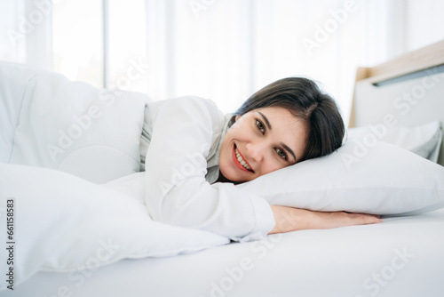 Young Woman Waking Up with Happiness in Cozy Bedroom at Home. Beautiful Girl Smiling and Relaxing in Bed after Waking Up.