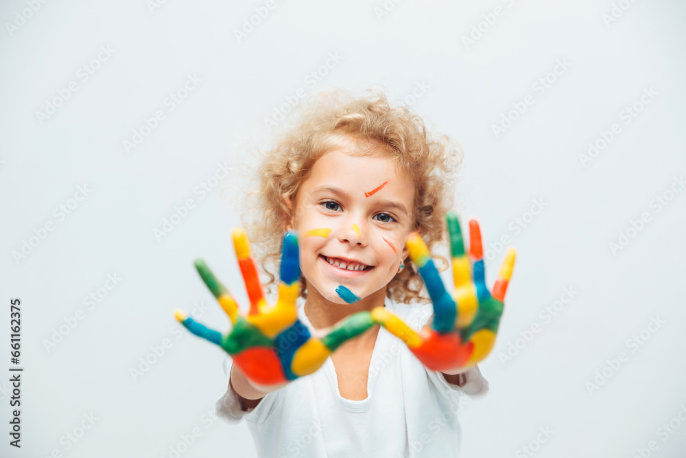 little blonde girl shows her hands painted with multi-colored paint on a white background. little blonde girl shows her hands painted with multi-colored paint on a white background.