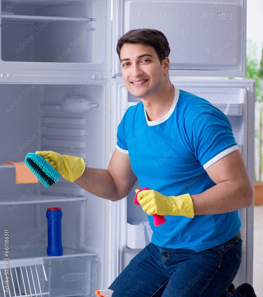 Man cleaning fridge in hygiene concept Man cleaning fridge in hygiene concept