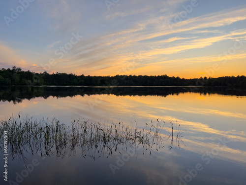 Sunset over fresh water lake with reeds in foreground