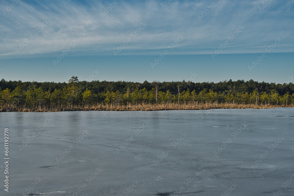 lake partially covered with ice during sunny day in winter season
