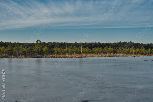 lake partially covered with ice during sunny day in winter season