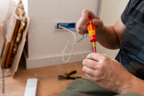 Close-up of an electrician working on an outlet in an apartment.