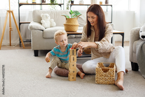 Mom and son playing with toy blocks in living room photo