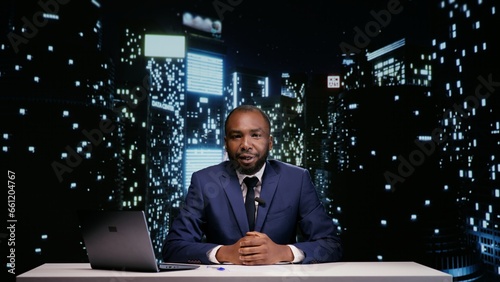 Happy tv host starting night talk show in newsroom, presenting world news and daily events live. African american man broadcasting news segment on midnight television program, reportage.