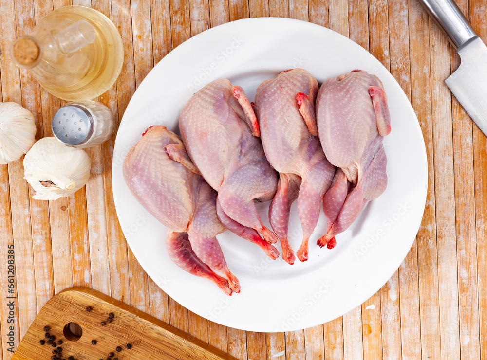 Quail carcasses lie on a cutting board. Small birds are prepared for cooking