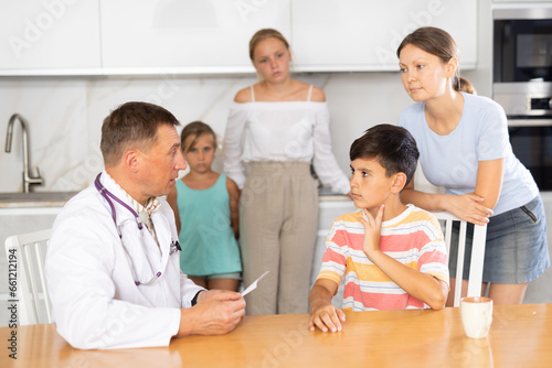 Quadro su tela Family doctor writes down complaints of the children of large family and writes