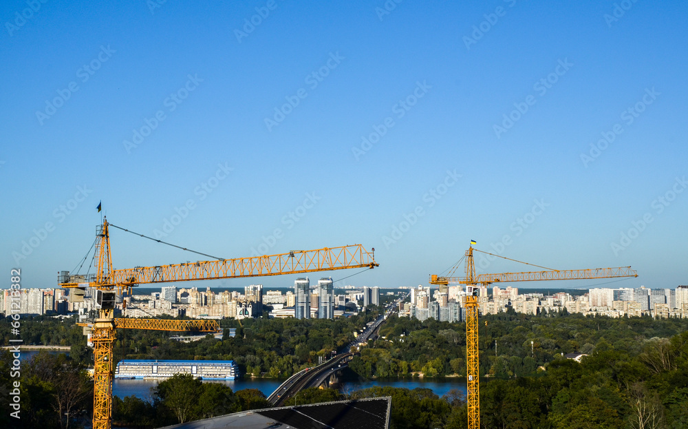 Tower crane on the background of Dnipro river and left bank of Kyiv city. New buildings architecture and industry construction