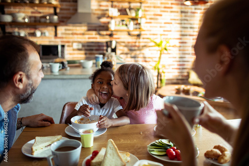 Young adoptive family having breakfast together in the kitchen at home