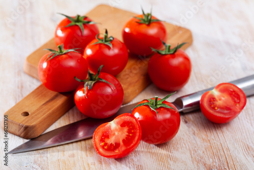 Red tomatoes and knife on wooden cutting board