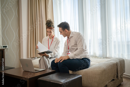 man and woman colleagues sit together in hotel room prepare for work