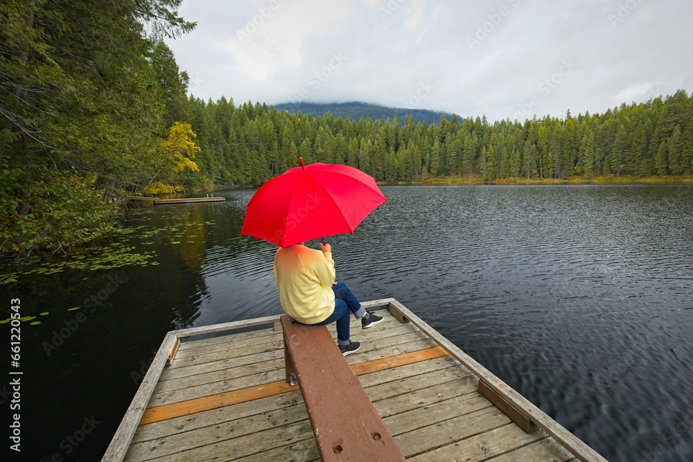 Woman holding umbrella enjoys the lake.