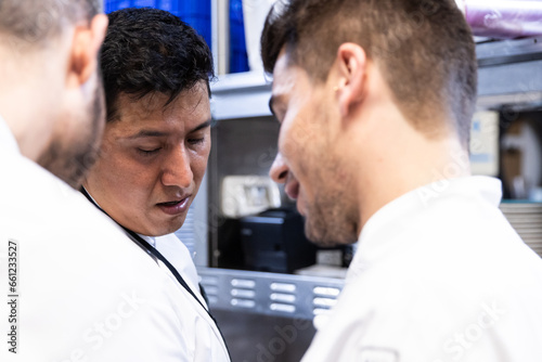 Focused photo of the face of the Latino chef with his Caucasian colleagues unfocused next to him