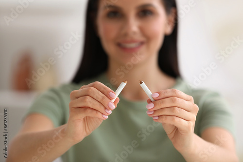 Stop smoking concept. Woman holding pieces of broken cigarette on blurred background, selective focus
