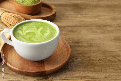 Cup of aromatic matcha latte on wooden table. Space for text