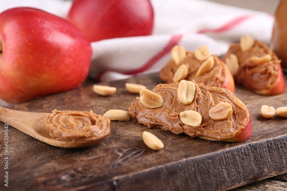Pieces of fresh apple with peanut butter on wooden board, closeup