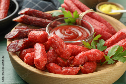 Different thin dry smoked sausages, parsley and ketchup on table, closeup