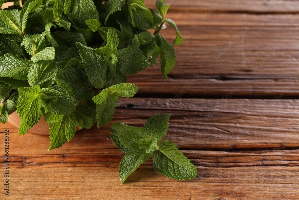 Bowl with fresh green mint leaves on wooden table, space for text Bowl with fresh green mint leaves on wooden table, space for text