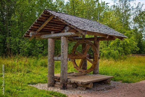 old wooden well with a roof against a background of green trees