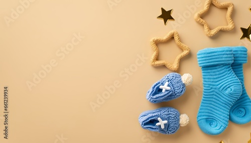 Baby accessories concept. Top view of blue tiny socks and gold stars on isolated pastel beige background with copy space