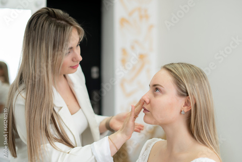 young female make-up artist working in the studio with model