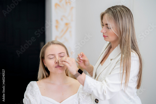 visagiste applies foundation with a sponge on the young woman's face