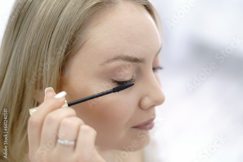 young woman doing her cosmetic treatment  using brush on her eyelash