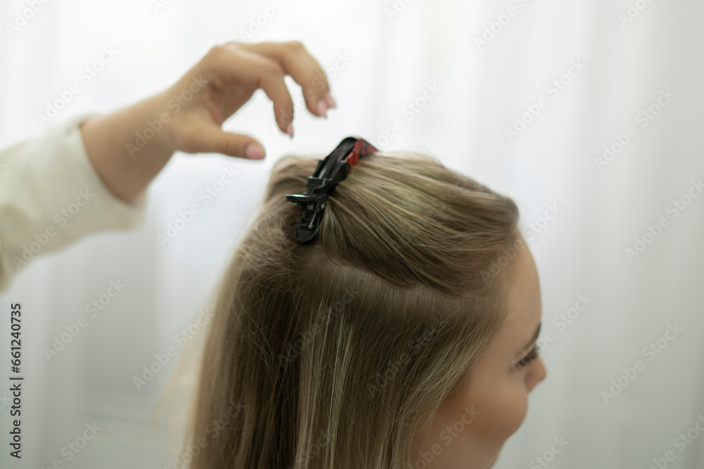 Fototapeta premium professional hair stylist puts a hairpin in the woman's hair in salon