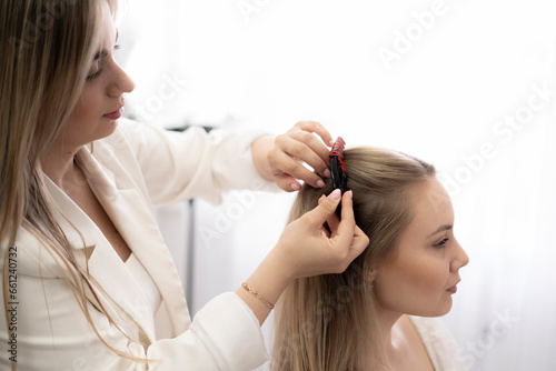 professional hair stylist puts a hairpin in the woman's hair in salon