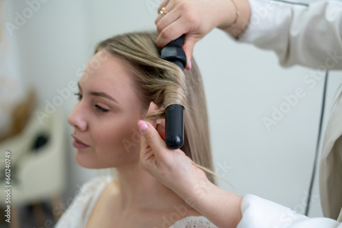 the expert stylist hairdresser doing work, making beautiful curls