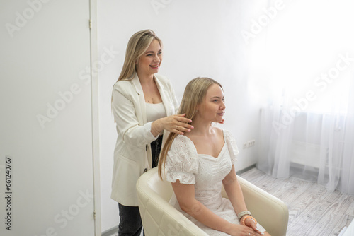 happy make-up artist working in the salon with young woman