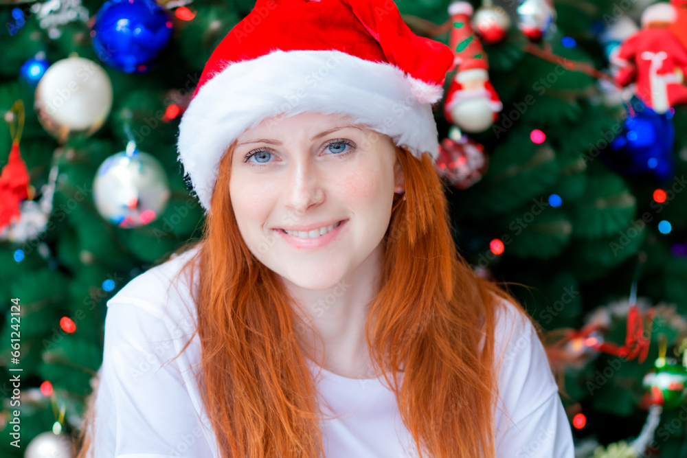Christmas portrait of a young red-haired woman in a white blouse with blue eyes