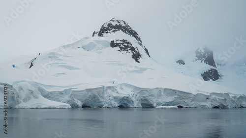 the snow-covered coast of Antarctica with a visible part of the rocks, a beautiful view from the sea