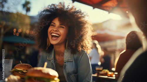 A happy woman eating a burger in an outdoor restaurant as a Breakfast meal craving deal. photo