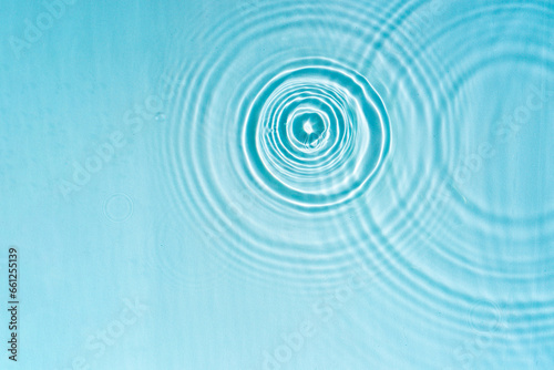 Patterns from Circles from drops on clear water Transparent blue water surface with ripples. Cosmetic moisturizing essence