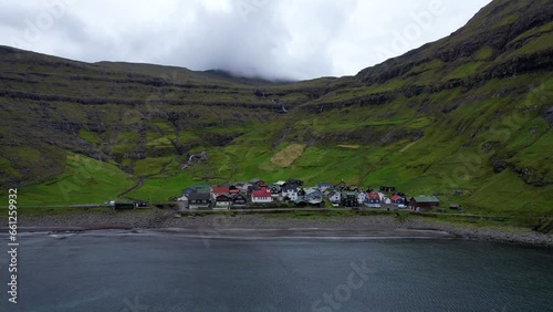 Aerial pullback shot of small Faroe village of Tjornuvik between mountains photo