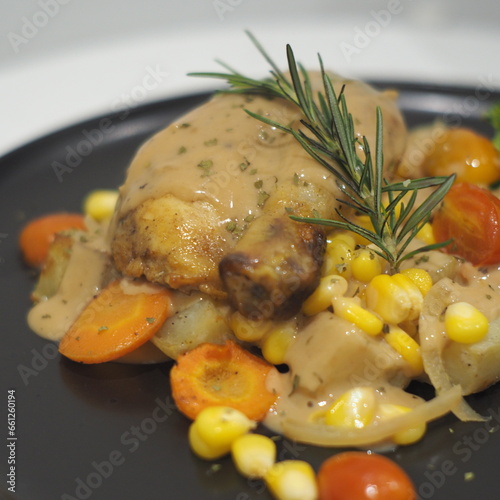Succulent roasted chicken, baked potatoes, mushroom sauce, and corn on a plate