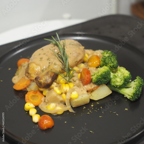 Succulent roasted chicken, baked potatoes, mushroom sauce, and corn on a plate