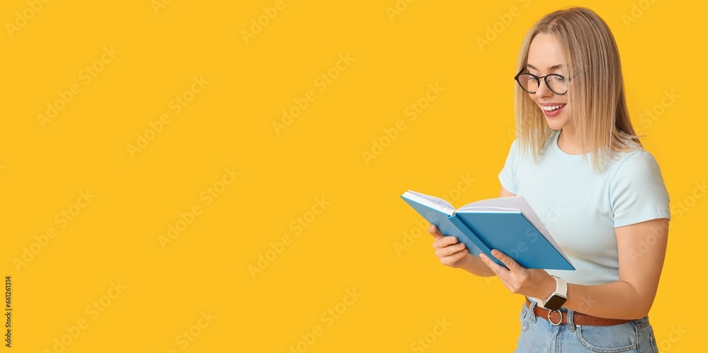 Beautiful young happy woman reading book on yellow background with space for text Beautiful young happy woman reading book on yellow background with space for text