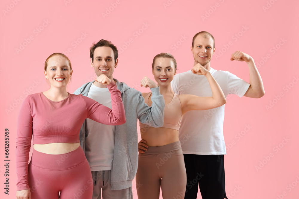 Group of sporty young people showing muscles on pink background Group of sporty young people showing muscles on pink background