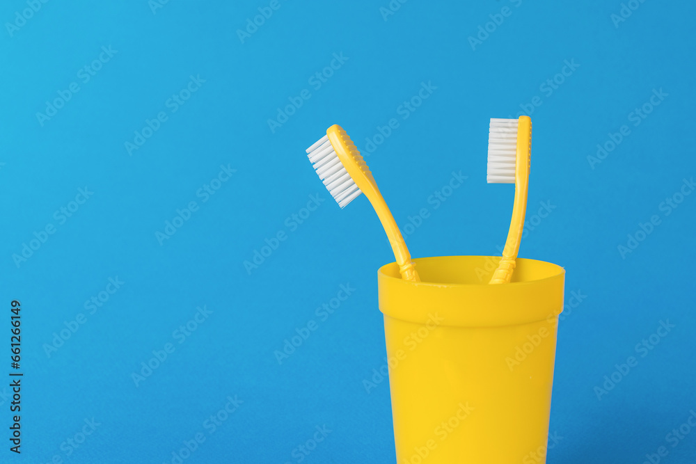 A pair of yellow toothbrushes on a bright blue background. A pair of yellow toothbrushes on a bright blue background.