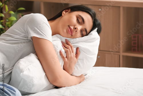 Young woman hugging soft pillow in bedroom