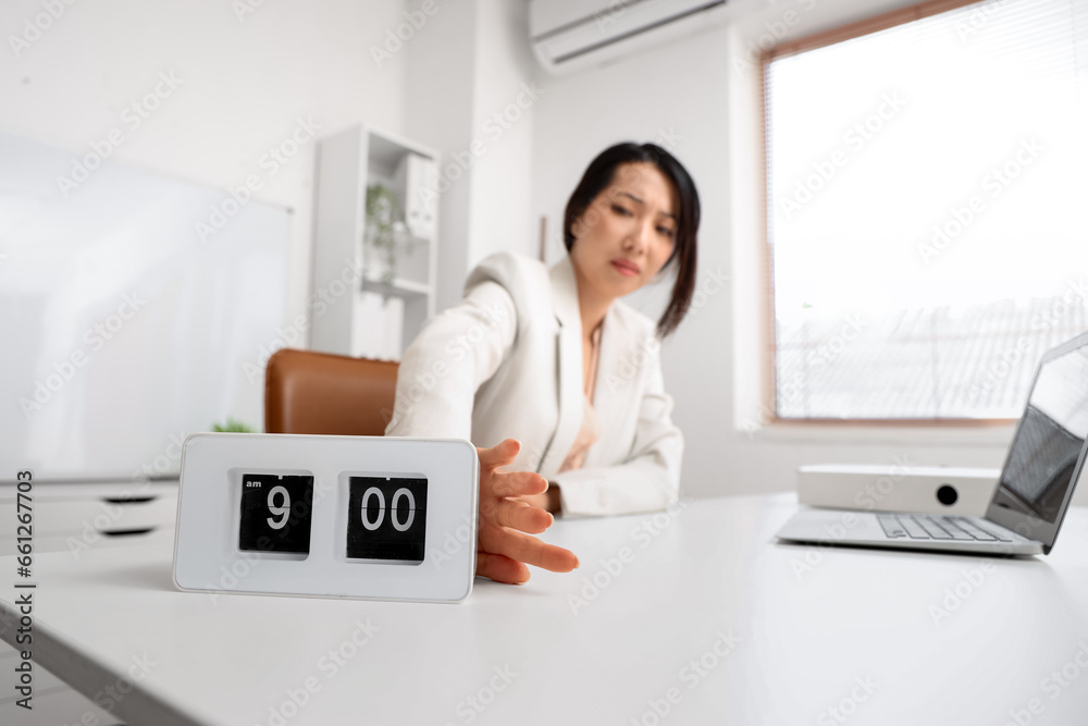Stressed Asian businesswoman with alarm clock in office, closeup Stressed Asian businesswoman with alarm clock in office, closeup