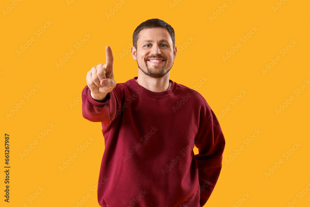 Handsome man using virtual screen on yellow background Handsome man using virtual screen on yellow background