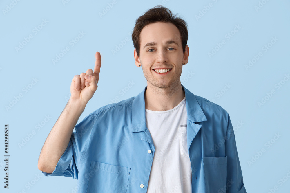 Young man pointing at something on blue background Young man pointing at something on blue background
